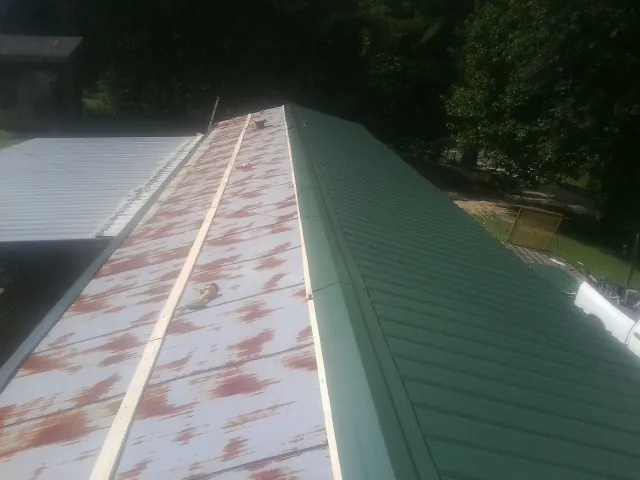 Old rusted panels beside newly installed green metal roofing — Wind Damage Roof Repair by Roofing Brothers in Spring Grove