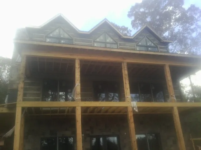 Dormers and porch framing on a large log home under construction — Roof Coating work by our crew in Spring Grove