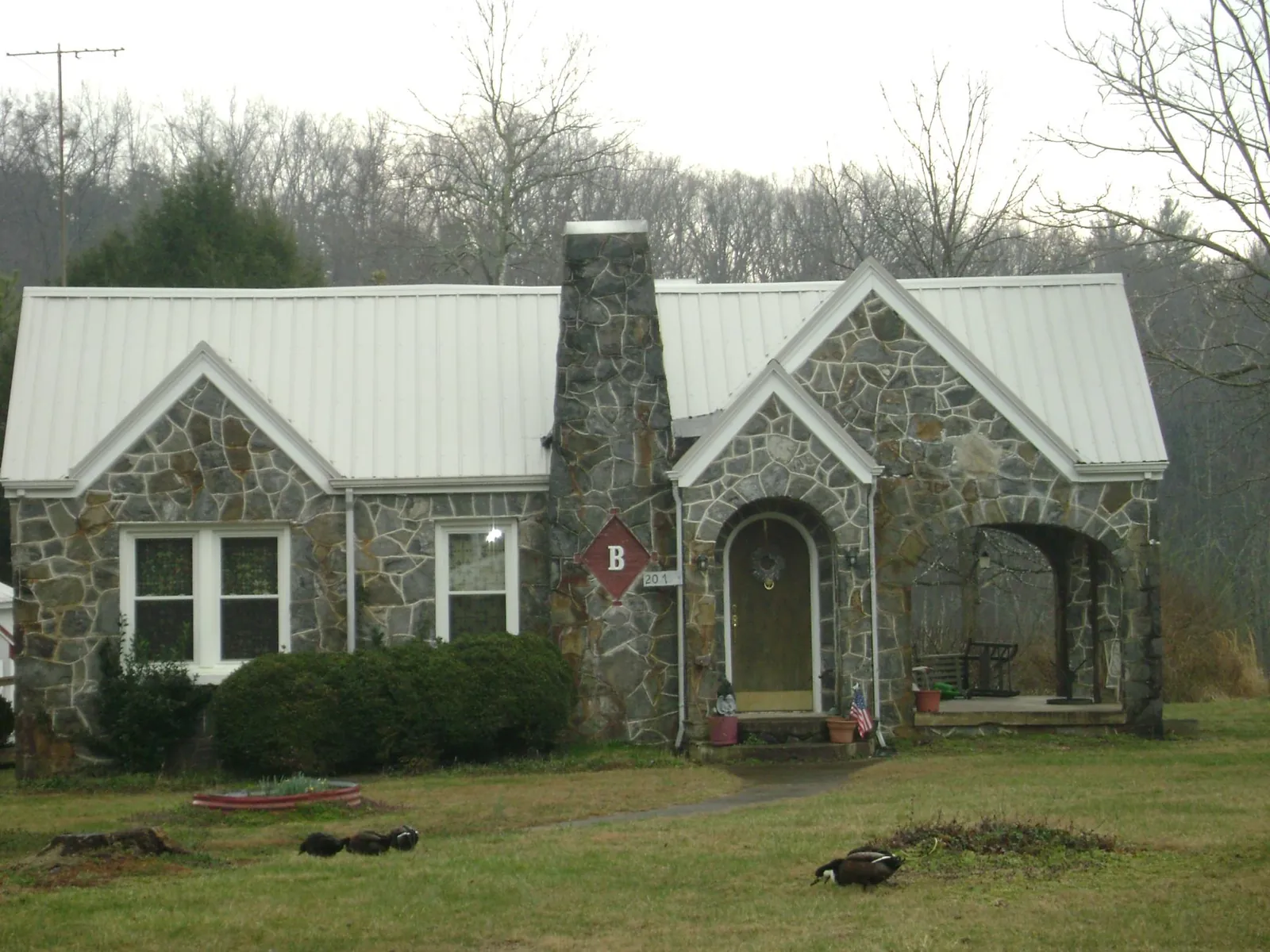 White metal roof on a stone cottage with steep gables in Spring Grove